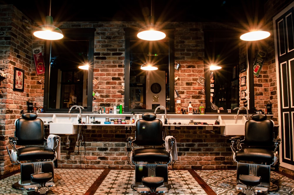Interior da Mad Dog Barbearia com cadeiras clássicas de couro e iluminação vintage